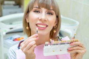 happy woman in dentistry picks up the color of tooth enamel photo