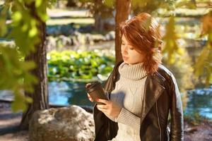 Portrait of a cheerful girl in nature with a glass of coffee photo