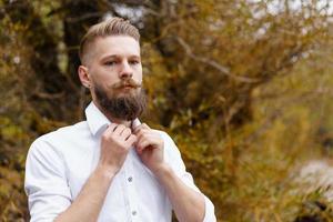 Portrait of pensive bearded attractive young man in white shirt looking photo