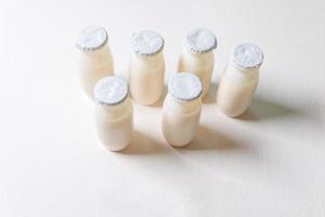 Small bottles with probiotics and prebiotics dairy drink on white background. Production with biologically active additives. Fermentation and diet healthy food. Bio yogurt with useful microorganisms. photo