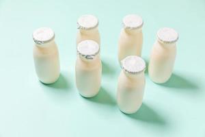 Small bottles with probiotics and prebiotics dairy drink on blue background. Production with biologically active additives. Fermentation and diet healthy food. Bio yogurt with useful microorganisms. photo