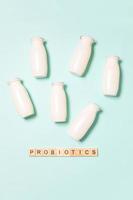 Small bottles with probiotics and prebiotics dairy drink on blue background. Production with biologically active additives. Fermentation and diet healthy food. Bio yogurt with useful microorganisms. photo