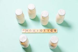 Small bottles with probiotics and prebiotics dairy drink on blue background. Production with biologically active additives. Fermentation and diet healthy food. Bio yogurt with useful microorganisms. photo
