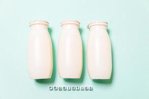 Small bottles with probiotics and prebiotics dairy drink on blue background. Production with biologically active additives. Fermentation and diet healthy food. Bio yogurt with useful microorganisms. photo