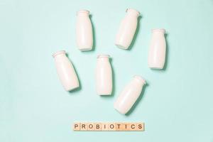 Small bottles with probiotics and prebiotics dairy drink on blue background. Production with biologically active additives. Fermentation and diet healthy food. Bio yogurt with useful microorganisms. photo