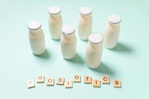 Small bottles with probiotics and prebiotics dairy drink on blue background. Production with biologically active additives. Fermentation and diet healthy food. Bio yogurt with useful microorganisms. photo