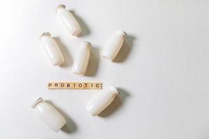 Small bottles with probiotics and prebiotics dairy drink on white background. Production with biologically active additives. Fermentation and diet healthy food. Bio yogurt with useful microorganisms. photo