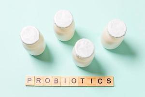 Small bottles with probiotics and prebiotics dairy drink on blue background. Production with biologically active additives. Fermentation and diet healthy food. Bio yogurt with useful microorganisms. photo
