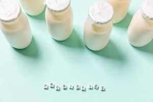 Small bottles with probiotics and prebiotics dairy drink on blue background. Production with biologically active additives. Fermentation and diet healthy food. Bio yogurt with useful microorganisms. photo