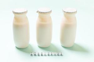 Small bottles with probiotics and prebiotics dairy drink on blue background. Production with biologically active additives. Fermentation and diet healthy food. Bio yogurt with useful microorganisms. photo