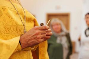 Iglesia Ortodoxa. cristiandad. manos de sacerdote sosteniendo aceite para ungir en el bautismo en el fondo tradicional de la iglesia ortodoxa. religión fe orar símbolo. celebración del bautismo ortodoxo. foto