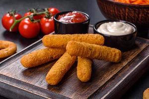 Breaded mozzarella cheese sticks served with tomato sauce photo