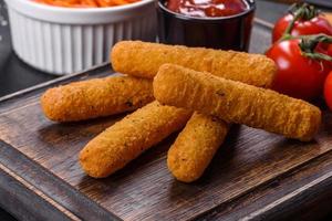 Breaded mozzarella cheese sticks served with tomato sauce photo