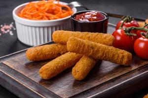 Breaded mozzarella cheese sticks served with tomato sauce photo