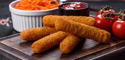 Breaded mozzarella cheese sticks served with tomato sauce photo