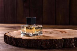 Glass perfume bottle with rosemary sprig on wooden podium photo