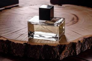 Glass perfume bottle with rosemary sprig on wooden podium photo