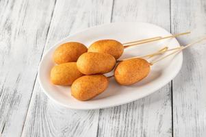 Corn dogs on white serving plate photo