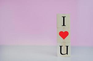 Wooden cubes with i love u symbol heart on the pink background and copy space. photo