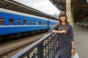 beautiful young woman standing on the platform of railway station travel concept photo