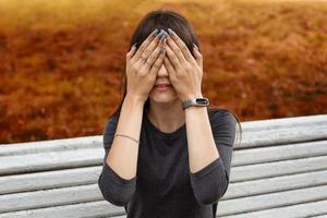 a young woman in the Park covered her face with her hands, the concept of resentment and disappointment, toning photo