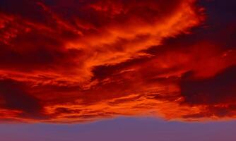 cielo naranja claro al atardecer con algunas nubes superficiales flujo abstracto nubes de trueno en el cielo al atardecer. foto