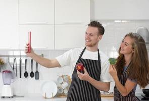 Young Couple Using Smartphone to Selfie While Cooking Healthy Breakfast in Kitchen at Home photo