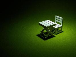 White wooden chair and table on artificial grass. Light shining down from above In the drak tone photo