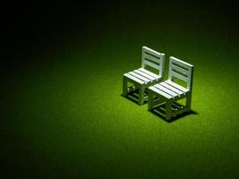 White wooden chairs on artificial grass. Light shining down from above In the dark tone low key photo