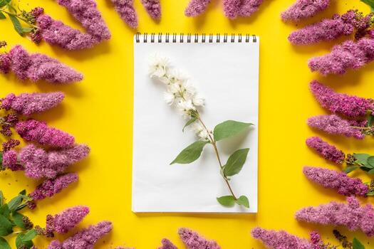 White summer flowers on a notebook. Yellow background. Layout. Flat lay, top view, copy space. photo