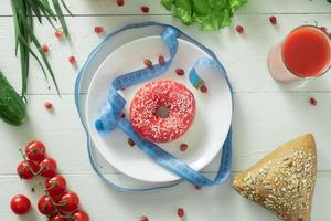 A delicious donut lies on a plate and eats to eat it. Problems of proper nutrition and the concept of choosing between wholesome and not wholesome food photo