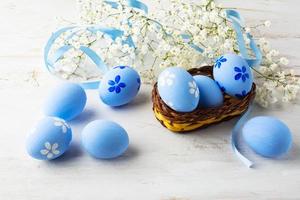 huevos de pascua azules en una pequeña canasta de mimbre foto