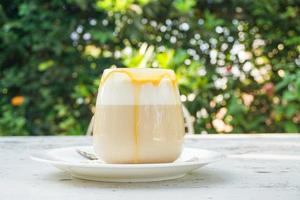 coffee caramel in glass jar on the table and nature green tree background - hot caramel macchiato coffee photo