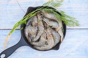 Fresh shrimp prawns for cooking food with green dill in the seafood restaurant, raw shrimps on bowl,  top view photo