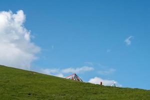 el cielo azul y las nubes blancas junto al lago qinghai, así como algunas tiendas de campaña y banderas de oración en la pradera foto