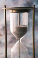 hourglass on table, sand flowing through the bulb of sandglass photo