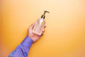 holding hand sanitizer on orange background top view photo