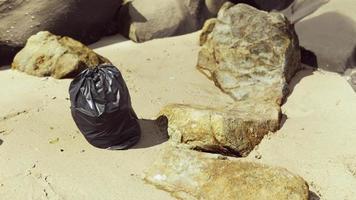 bolsa de basura de plástico negro llena de basura en la playa video
