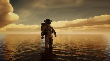 Raumfahrer im Meer unter Wolken bei Sonnenuntergang