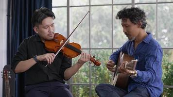 deux musiciens asiatiques jouant du violon et de la guitare en studio video