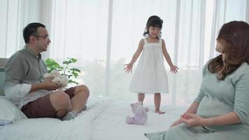 familia embarazada con una hija pequeña jugando al oso de peluche juntos en el dormitorio video