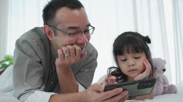 alejarse de padre e hija viendo dibujos animados desde el teléfono inteligente juntos en casa video