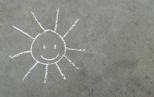 sun with a smile is drawn in chalk on the asphalt. banner with place for your text, copy space. children creativity, summer joy emotion photo