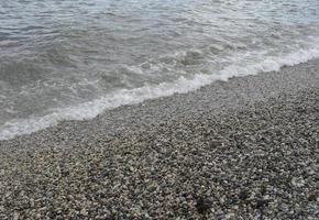 sea wave with foam on the shore with pebbles. background, banner, summer, travel photo