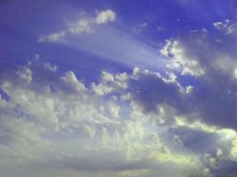 rays of the sun through white clouds in a blue sky natural background photo