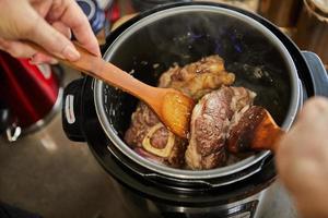 Ossobuco with spindle Beef is fried in pressure cooker and mixed with wooden spatulas. French gourmet cuisine photo