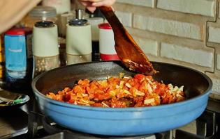 Tomato sauce, mushrooms and capers are fried in pan on gas stove for cooking Veal tongue. French gourmet cuisine photo