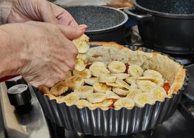 Cooking Winter cake With apricots, plums, bananas and pineapple. French gourmet cuisine photo