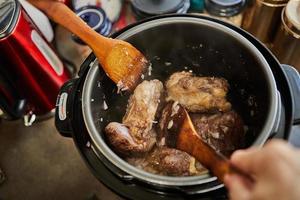 Ossobuco with spindle Beef is fried in pressure cooker and mixed with wooden spatulas. French gourmet cuisine photo