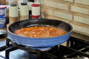 Tomato sauce, mushrooms and capers are fried in pan on gas stove for cooking Veal tongue. French gourmet cuisine photo